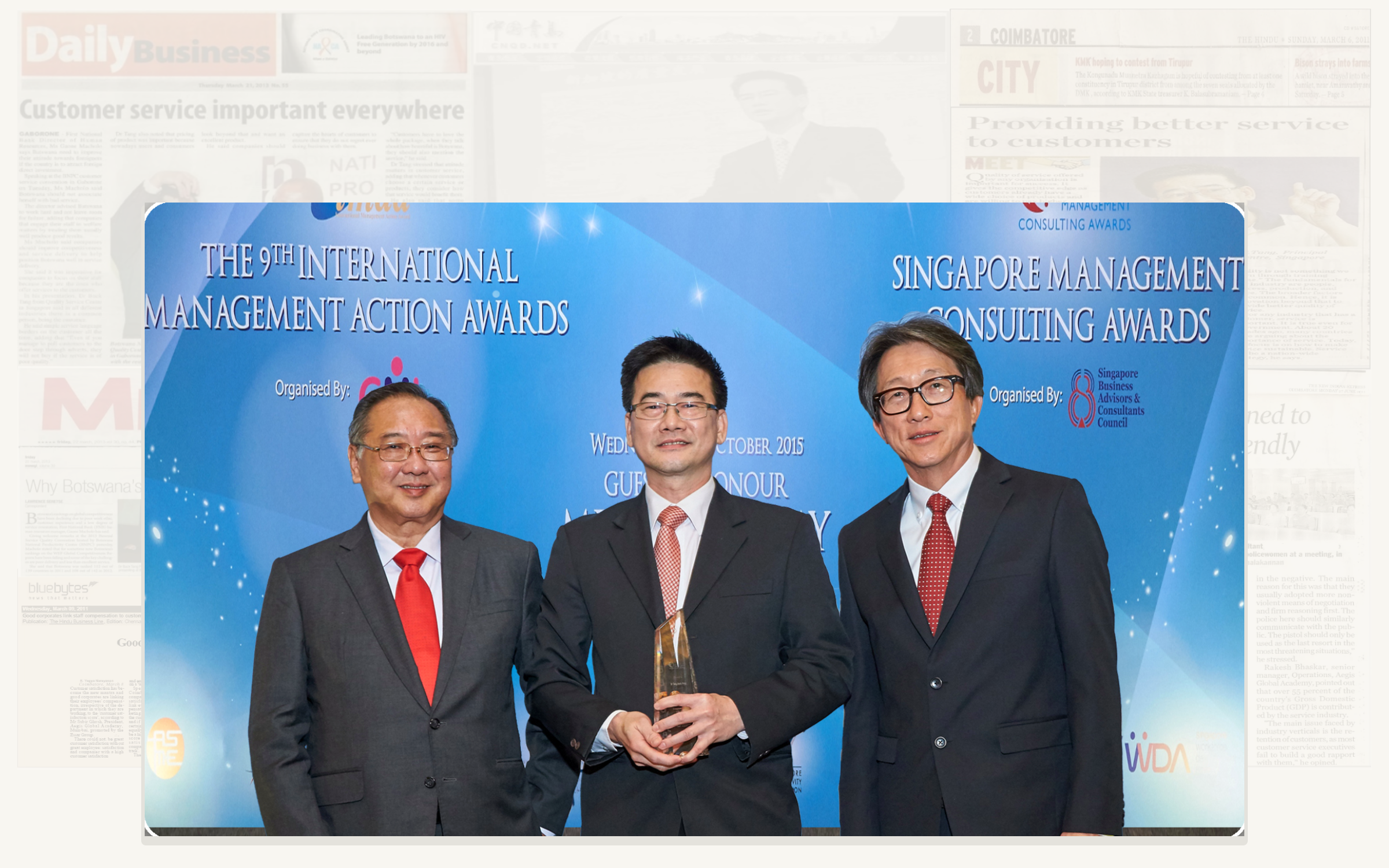 Original SE Associates award presentation photograph with its subtle newspaper and media background retained unchanged.
